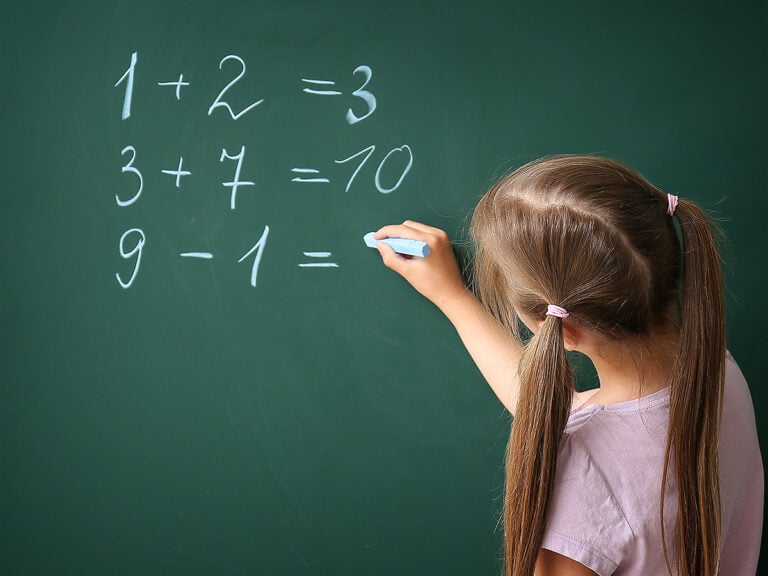 Girl doing math problems on blackboard