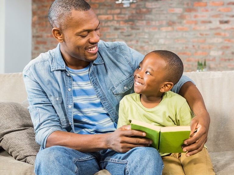 Father and pre-k son reading on the couch