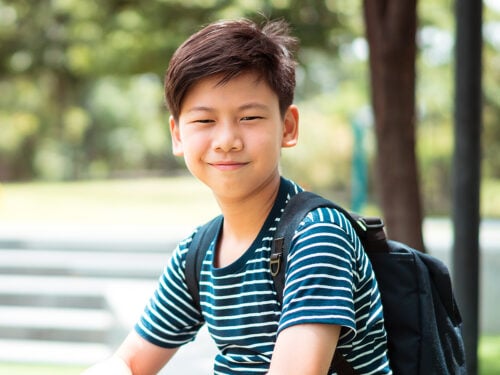 boy smiling outside wearing backpack