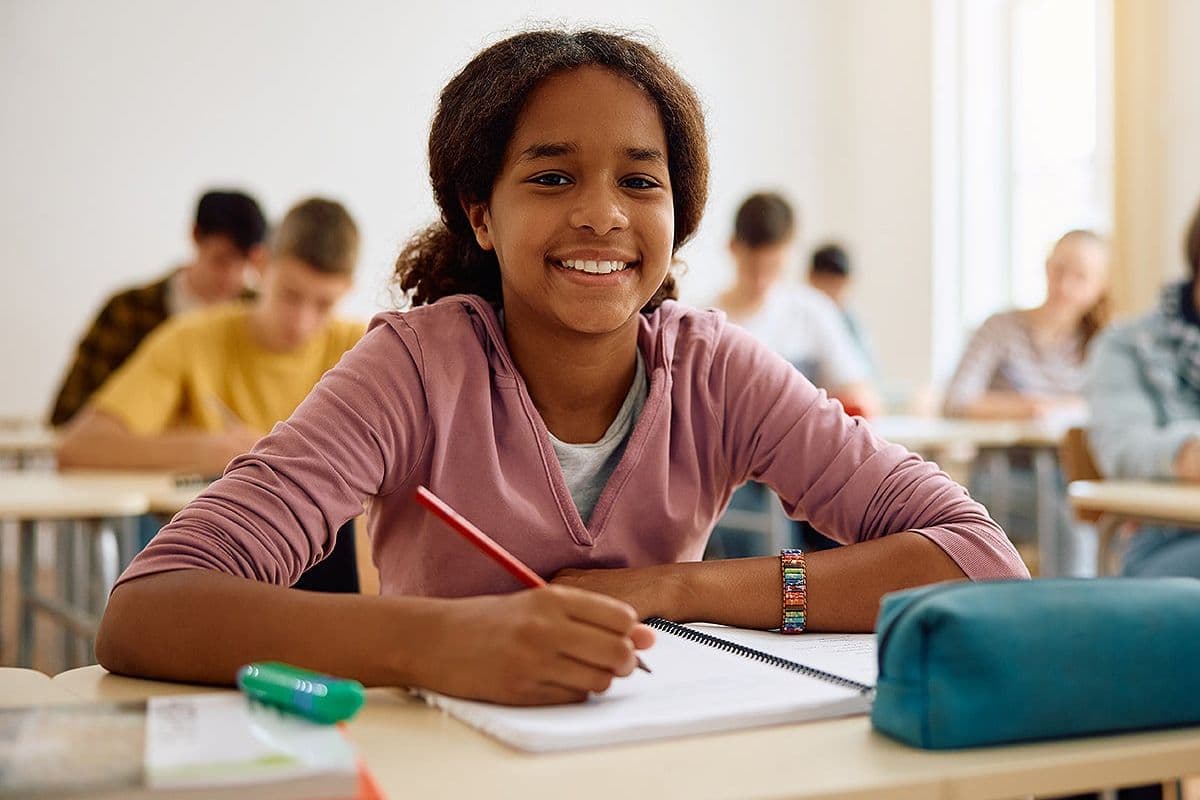 Smiling teenage girl taking notes in class