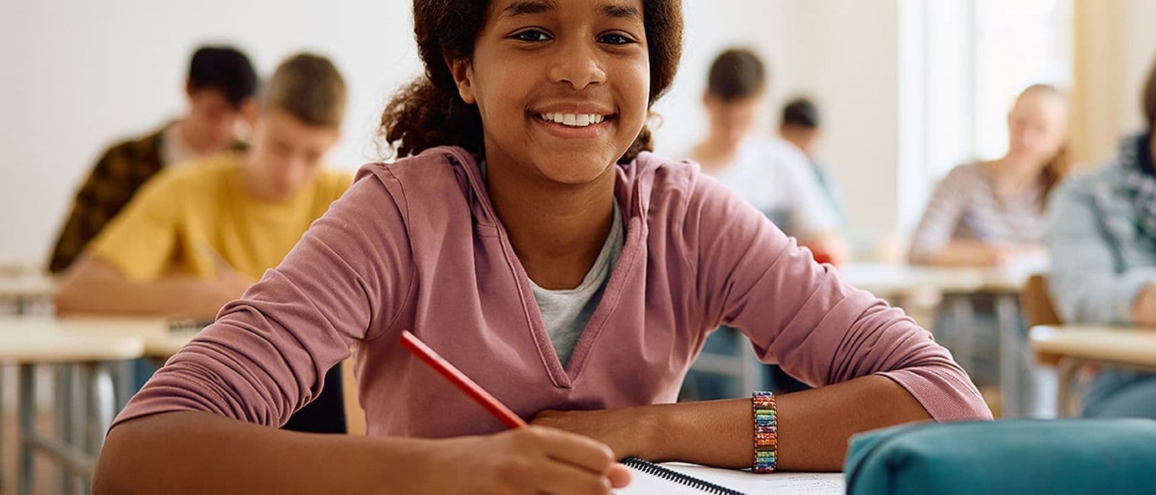 Smiling teenage girl taking notes in class