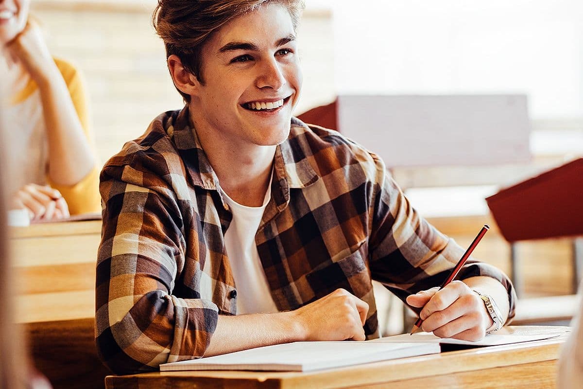 Teenage boy smiling during lecture in high school classroom