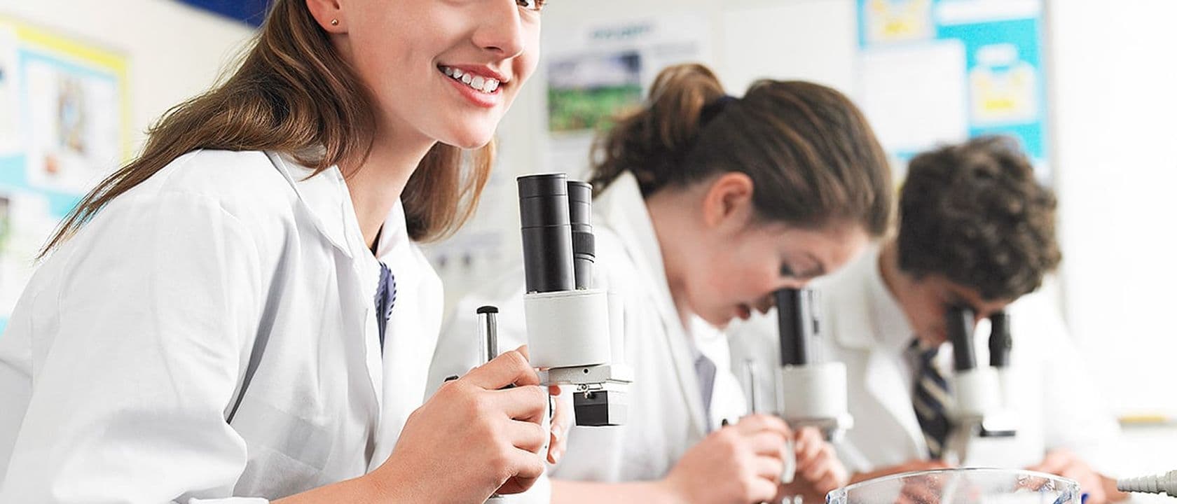 High school students using microscopes in laboratory