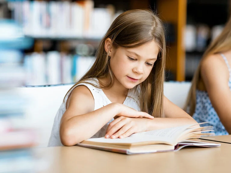 Little girl reading book in library