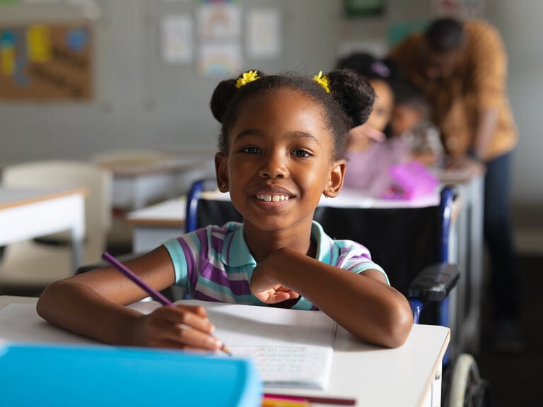 Portrait of smiling elementary girl at her desk in school
