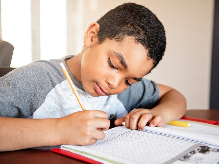 Young child doing homework in notebook at home