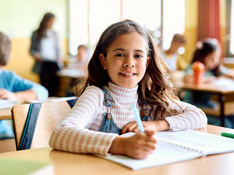 Smiling young girl taking notes in class