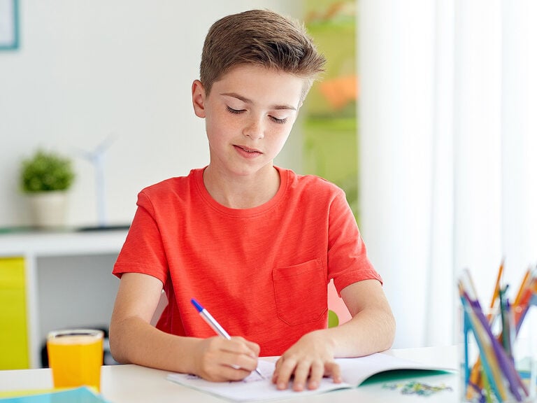 Young boy writing at desk at home