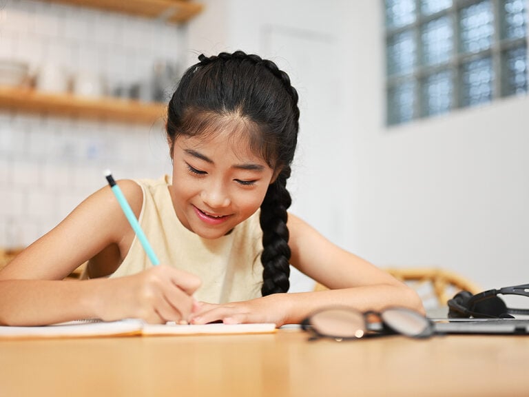 Young smiling girl doing homework at desk