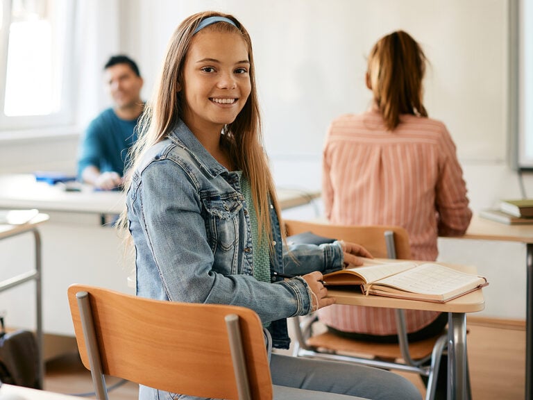 Happy high school student sitting in class and looking at camera.