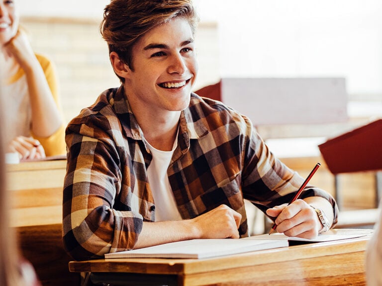 Teenage boy smiling during lecture in high school classroom