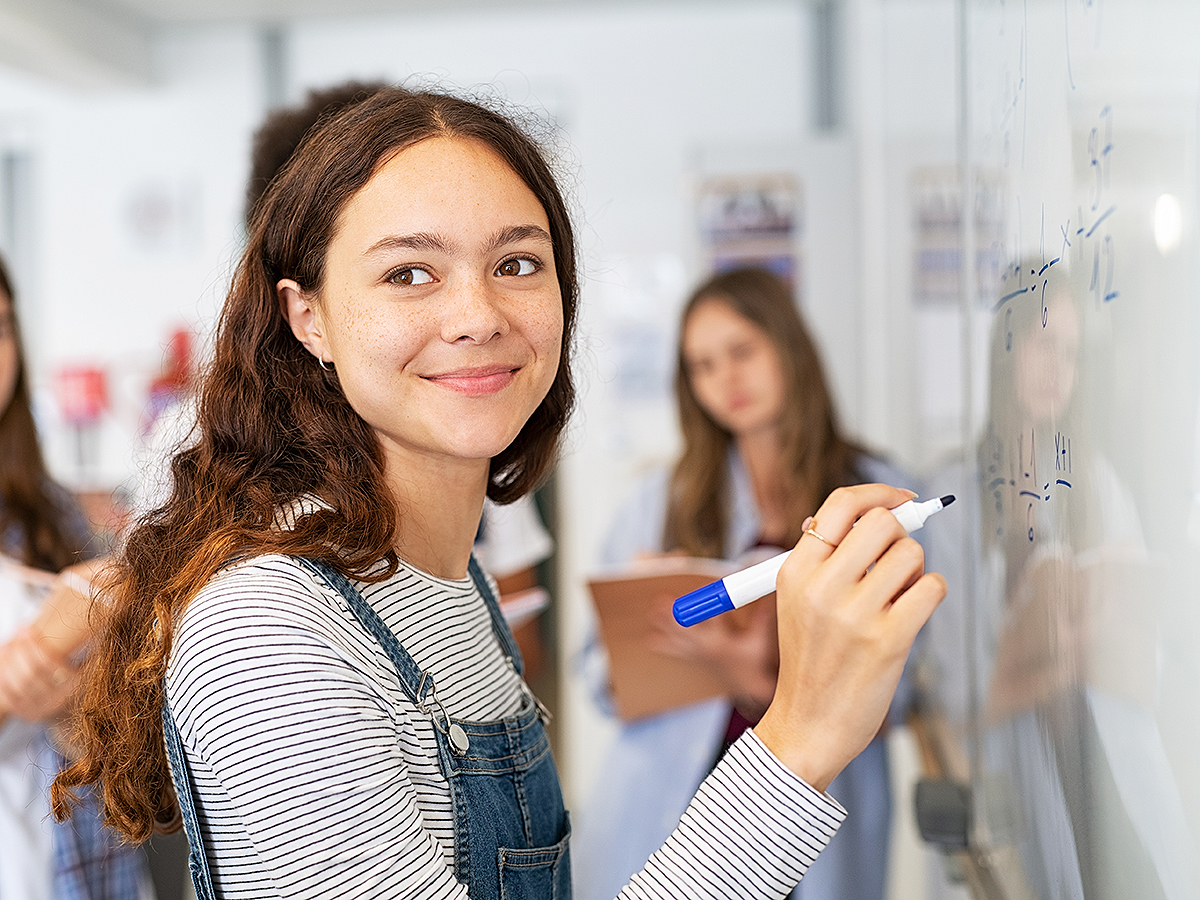 high school girl doing math on whiteboard at school