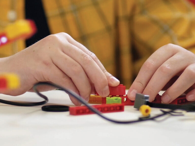 Close up of child working with LEGOs for STEM class