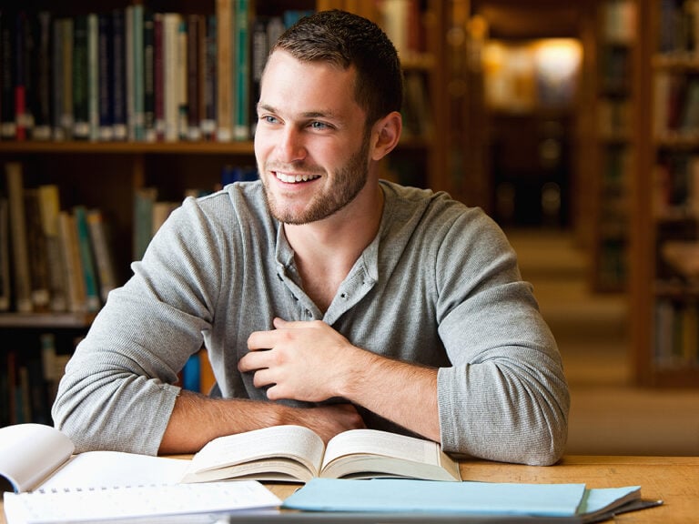 Smiling male student working in a library