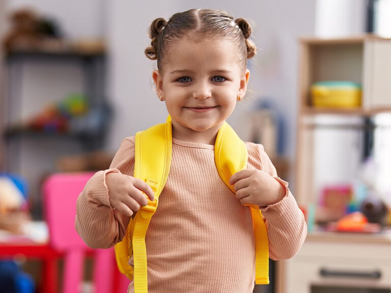 Kindergarten girl smiling with backpack at school