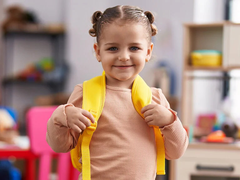 Kindergarten girl smiling with backpack at school