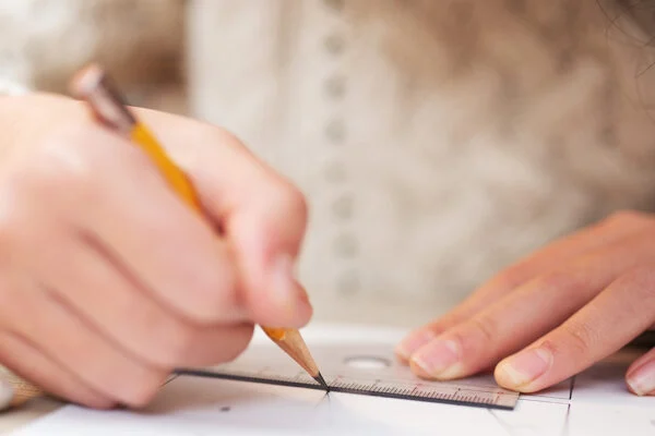 child doing math homework, using a ruler to measure shape