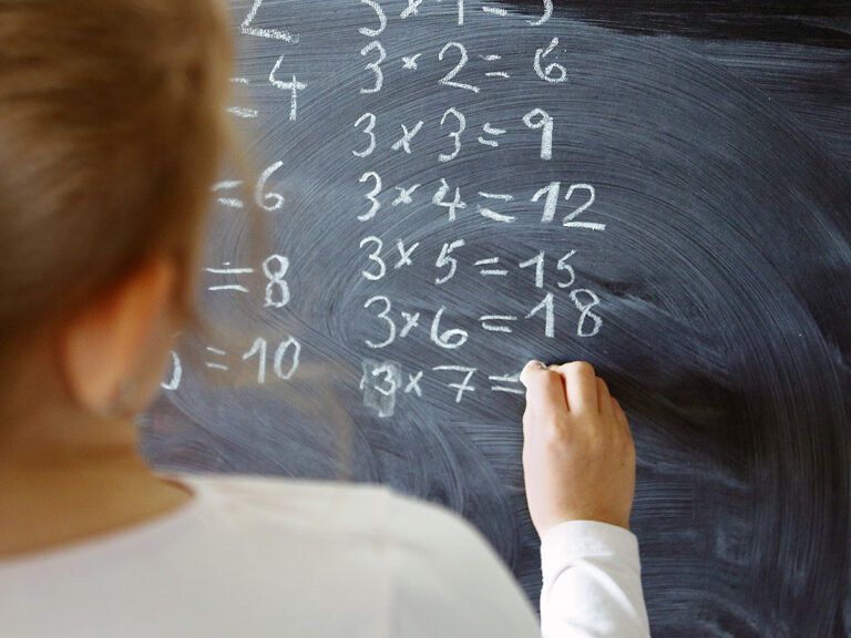 Girl doing multiplication problems on blackboard
