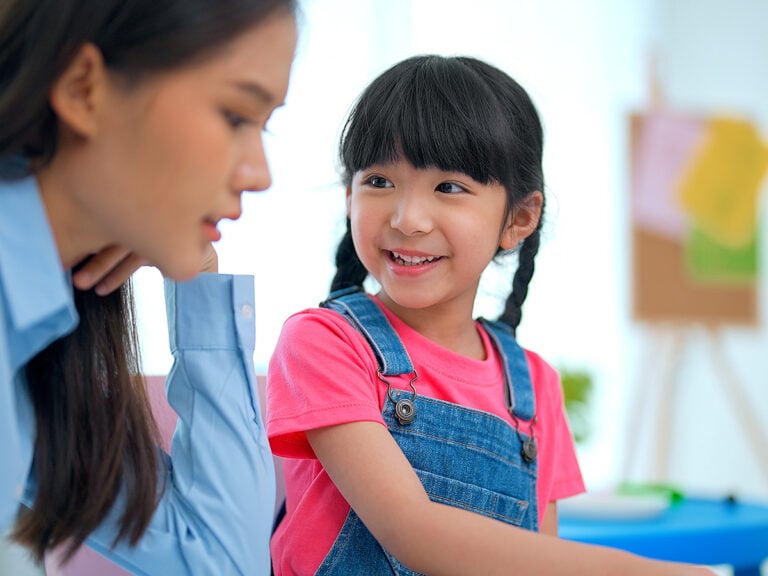 kindergarten girl communicating and consulting with teacher