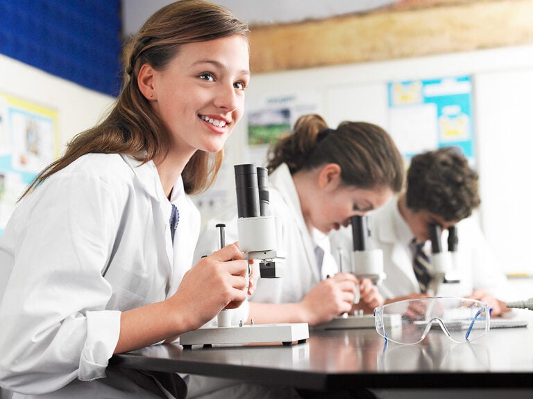 Students Using Microscopes In Laboratory
