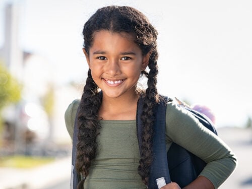 Portrait of smiling elementary school girl with backpack